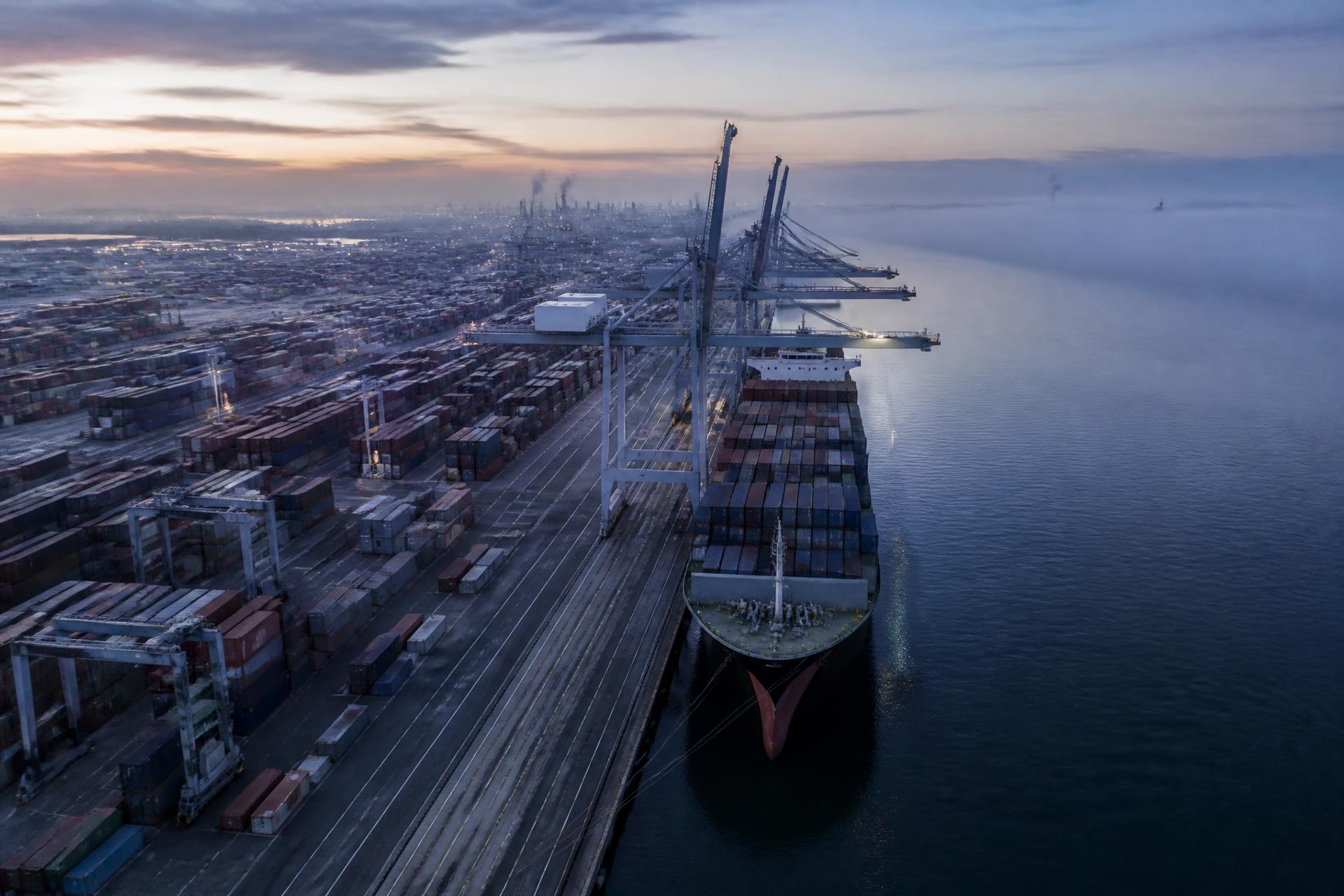 Container terminal at dawn with gantry cranes and stacked shipping containers